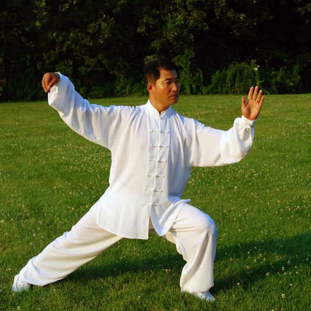 Man practicing Tai Chi outdoors in a peaceful green setting